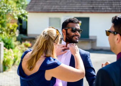 Gast hilft Bräutigam bei Trauung in St. Vitus nahe München, Hochzeit im Freien, Hochzeitsreportage in Oberbayern.