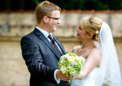 Brautpaar lacht mit Blumenstrauss bei Hochzeitsshooting im Kloster Fuerstenfeld, festgehalten vom Hochzeitsfotografen.