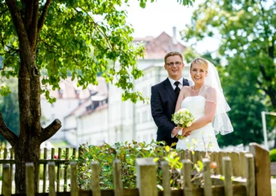 Brautpaar laechelnd bei Hochzeitsfotosession im Kloster Fuerstenfeld, umgeben von Natur. Hochzeitsfotografie nahe Muenchen.