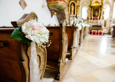 Kirchliche Trauung in Ottendichl bei München, Kirchenbank mit Blumen dekoriert. Hochzeitsfotografie Oberbayern.