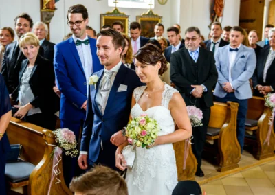 Brautpaar geht bei kirchlicher Trauung in der Dorfkirche Moosach. Hochzeit in Oberbayern, Hochzeitsfotografie.