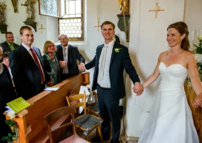 Brautpaar haelt bei kirchlicher Hochzeit Gäste an Haenden, Gut Georgenberg. Hochzeitsfotografie in Oberbayern.