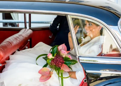 Braut im Auto mit Blumenstrauss nach der kirchlichen Trauung, Hochzeitsfoto nahe Muenchen.