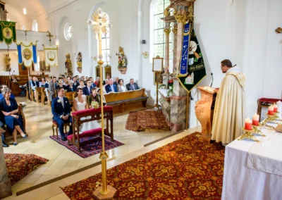 Kirchliche Trauung bei einer Hochzeit in der Dorfkirche Moosach, Bayern. Brautpaar vor Altar mit Kerzen.