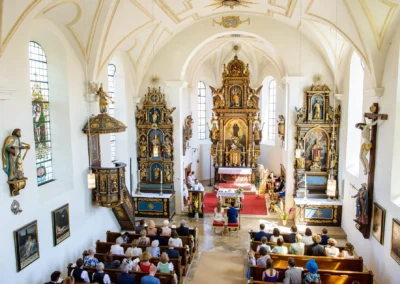 Innenaufnahme kirchliche Trauung in St. Benedikt Gelting, Hochzeitsfotografie mit Altar und Gaesten.