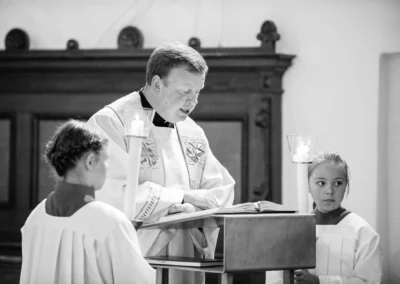 Priester bei kirchlicher Trauung in Osterwarngau, begleitet von Ministranten mit Kerzen. Hochzeitsfotografie in Bayern.