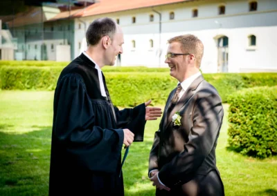 Freie Trauung im Garten, Bräutigam im Gespräch mit Pastor. Hochzeitsfotograf nahe München. Ort: Fürstenfeldbruck.