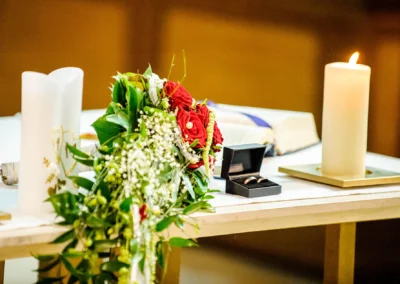 Kerzen, Ringe, Blumenstrauss auf Altar bei kirchlicher Trauung in Frauenkirche Osterwarngau. Hochzeitsfotografie Bayern.