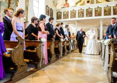 Braut schreitet mit Vater den Gang der Kirche in Ottendichl bei München entlang, Hochzeitsfoto einer Trauung.