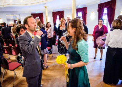 Gäste feiern mit Sekt bei einer standesamtlichen Trauung im Kurhaus Bad Tölz, bunte Kleidung und fröhliche Stimmung.
