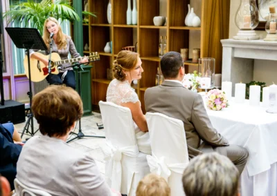 Freie Trauung im Gasthof Stangl, Musikerin spielt Gitarre, Braut und Bräutigam vorne, Teil der Hochzeitsreportage.