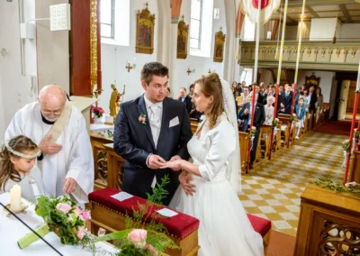 Brautpaar tauscht Ringe bei kirchlicher Trauung in der Kirche Mariae Heimsuchung. Hochzeitsfotografie in Oberbayern.