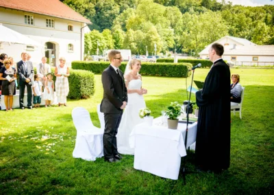 Brautpaar bei freier Trauung im Freien nahe München, umgeben von Gästen in Kloster Fuerstenfeld. Hochzeitsreportage.
