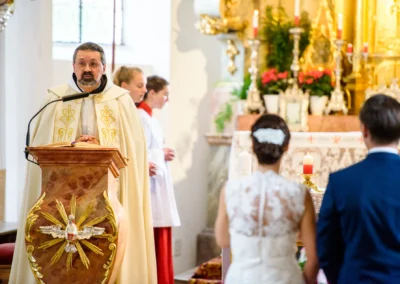 Priester bei kirchlicher Trauung in der Dorfkirche Moosach, Hochzeitspaar im Vordergrund, Hochzeitsfotografie.