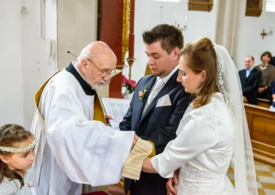 Priester segnet Brautpaar bei der kirchlichen Trauung in der Kirche Mariae Heimsuchung in Oberbayern. Hochzeitsfotografie.