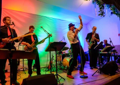 Band spielt bei Hochzeit nahe Starnberger See, Auftritt mit bunter Buehne und Saenger. Hochzeitsfotograf in Aktion.