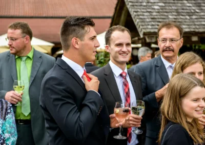 Gäste in festlicher Kleidung bei einer Hochzeitsfeier mit Getränken auf Gut Georgenberg, Hochzeitsfotografie.