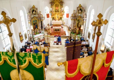 Kirchliche Trauung in der Dorfkirche Moosach mit dekorierten Bannern und Hochzeitspaar vor dem Altar in Oberbayern.