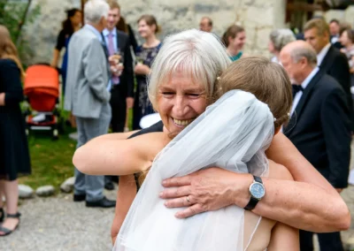 Braut umarmt Gast bei Hochzeitsfeier im Freien, Hochzeitsreportage auf Gut Georgenberg, südöstlich von Muenchen.