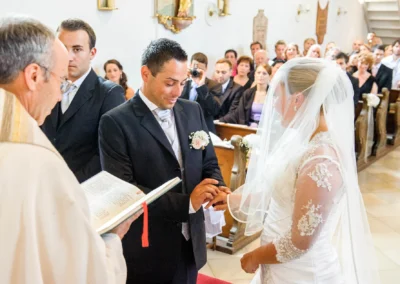 Bräutigam steckt der Braut bei kirchlicher Trauung in Ottendichl bei München den Ring an. Hochzeitsfotografie.