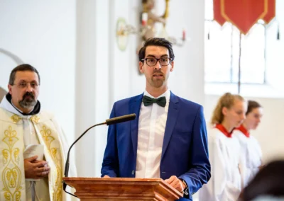 Mann im blauen Anzug spricht während der kirchlichen Trauung in der Dorfkirche Moosach, fotografiert in Bayern.