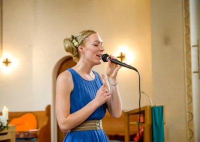 Sängerin in blauer Robe bei kirchlicher Trauung in Oberbayern, festgehalten von einem Hochzeitsfotografen.