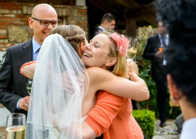 Braut umarmt Gast bei Hochzeit auf Gut Georgenberg. Feierliche Stimmung festgehalten in Hochzeitsreportage.