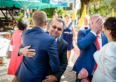 Gäste bei Hochzeit im Gasthof Widmann, fröhliche Umarmung, Emotionen festgehalten in der Hochzeitsreportage.