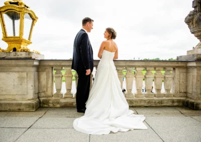 Brautpaar steht auf einer Terrasse aus Stein, Blick aufeinander gerichtet, links eine verzierte, goldene Laterne, darunter Parklandschaft.
