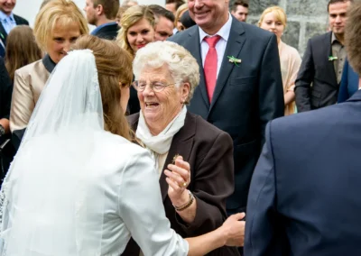 Braut begrüßt ältere Dame nach kirchlicher Trauung in der Kirche Mariä Heimsuchung, Hochzeitsfoto Holzkirchen.