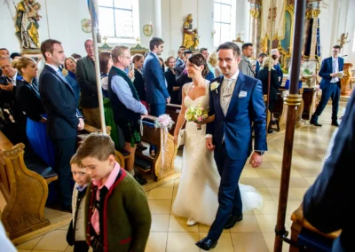 Brautpaar verlässt bei kirchlicher Trauung die Dorfkirche Moosach, glückliche Gäste applaudieren, Hochzeitsfotografie.