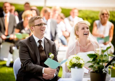Lachendes Brautpaar bei der freien Trauung im Freien in Oberbayern, festgehalten von einem Hochzeitsfotografen.