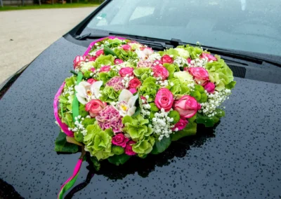 Blumenherz auf einer Motorhaube bei Hochzeit, Gut Schloss Sulzemoos. Hochzeitsfotografie im Freien bei Regenwetter.