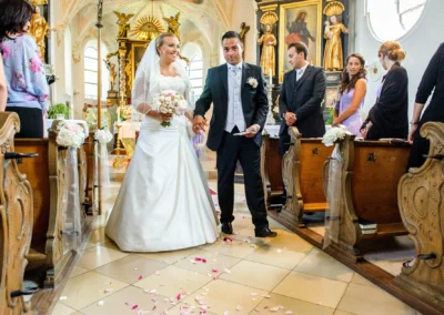 Brautpaar bei kirchlicher Trauung in Ottendichl bei Muenchen, festgehalten von Hochzeitsfotograf. Petals am Boden.
