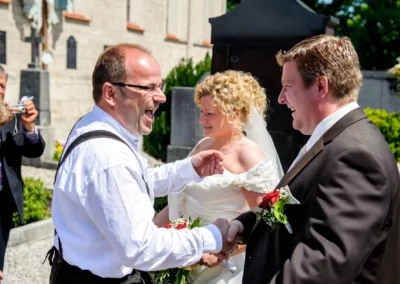 Hochzeit in Osterwarngau, Brautpaar und Gast lachen bei kirchlicher Trauung im Freien, Hochzeitsreportage.