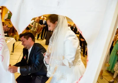 Brautpaar schneidet Stoffherz aus bei Hochzeit in Oberbayern, umgeben von Gaesten. Hochzeitsfotografie nahe Muenchen.