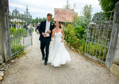 Brautpaar laechelt beim Auszug durch Tor an Hochzeit in Glonn, festgehalten von Hochzeitsreportage aus Oberbayern.