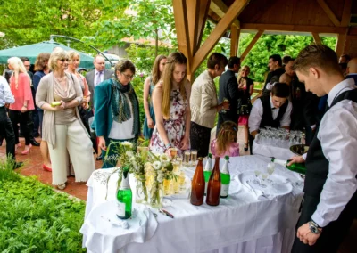 Gaste bei Hochzeit auf Gut Schloss Sulzemoos, bedienen sich am Sektempfang. Hochzeitsfoto im Freien unter Pavillon.