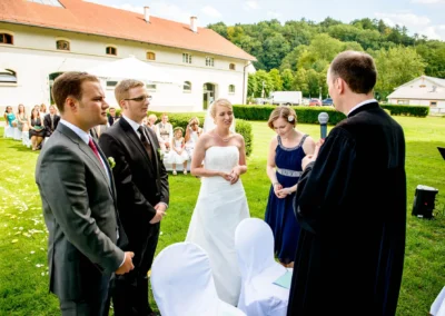 Freie Trauung im Freien bei einer Hochzeit im Kloster Fuerstenfeld. Brautpaar und Gaeste bei der Zeremonie.