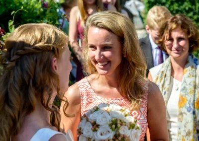 Braut und Gast bei Hochzeit nahe Starnberger See lachend im Garten. Hochzeitsfotograf hat den Moment eingefangen.