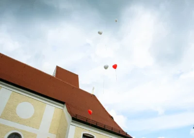 Luftballons steigen ueber einem Hochzeitsort in Moosach bei Grafing auf, festgehalten in einer Hochzeitsreportage.