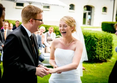 Brautpaar lacht bei freier Trauung im Freien in Oberbayern, festgehalten von Hochzeitsfotograf.