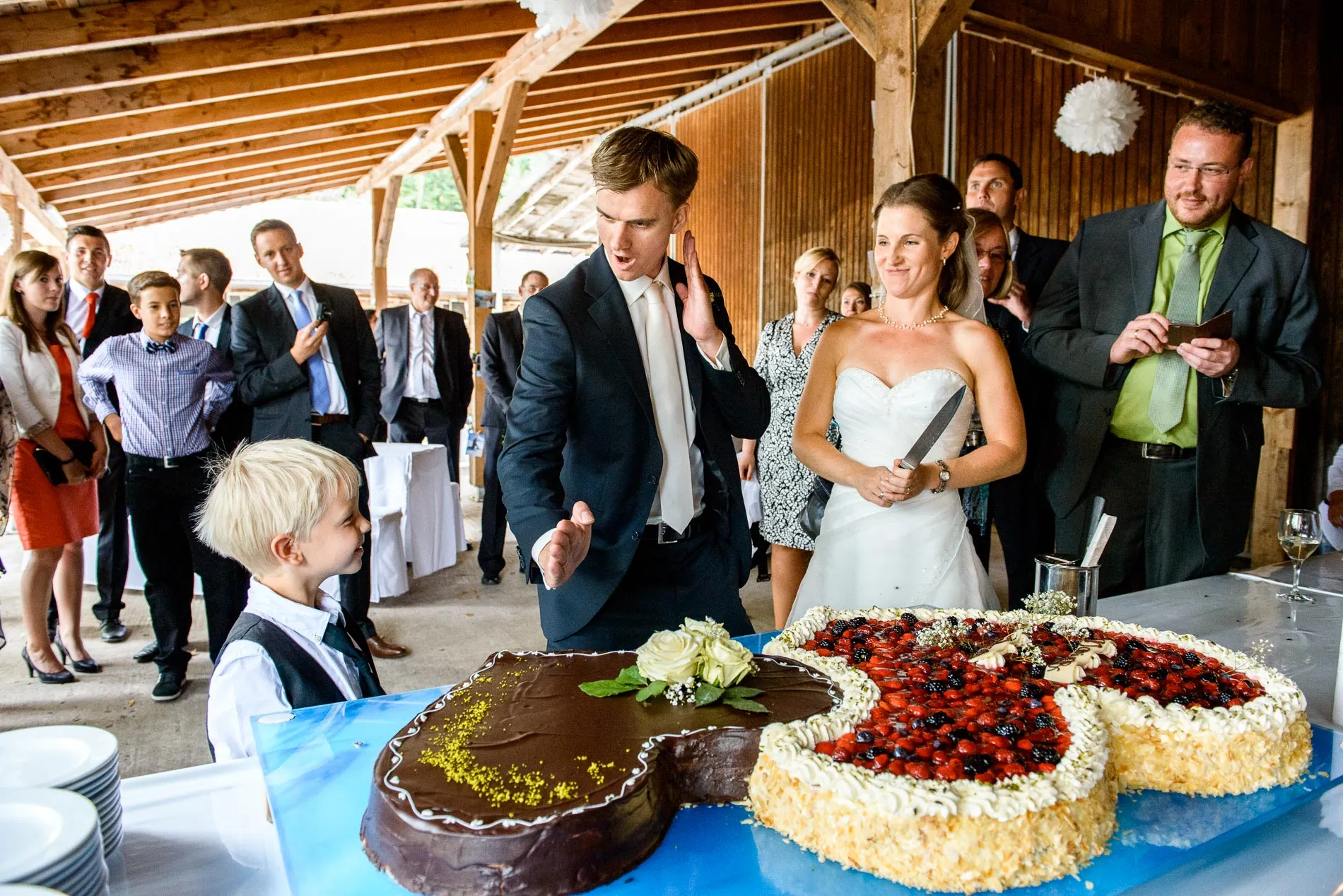 Brautpaar beim Anschneiden der Hochzeitstorte auf Gut Georgenberg, umgeben von Gästen, Hochzeitsreportage.