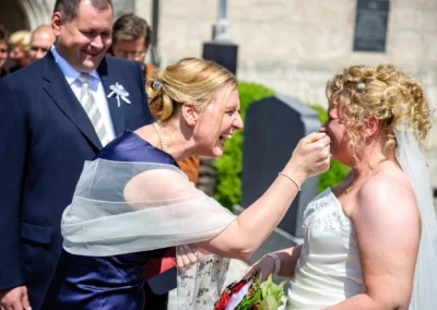 Braut bei kirchlicher Trauung in Osterwarngau lacht mit einer Freundin: Ein Herzmoment der Hochzeitsfotografie.