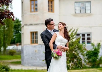 Brautpaar vor Schloss Sulzemoos, lachend und romantisch bei ihrem Hochzeitsshooting im Gruenen. Hochzeitsfotografie.