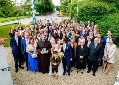 Große Hochzeitsgesellschaft draußen in Moosach bei Grafing. Brautpaar mittig, Gäste umringt. Hochzeitsfoto.