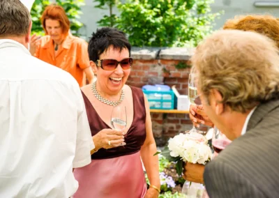 Lachende Gaeste bei einer Hochzeitsfeier in der Alten Gaertnerei Taufkirchen, festgehalten von einem Hochzeitsfotografen.