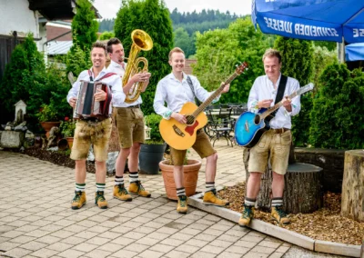 Eine Band in Tracht spielt bei einer Hochzeit in Moosach bei Grafing im Freien. Hochzeitsreportage in Oberbayern.