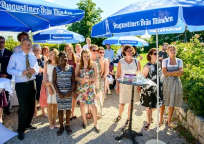 Hochzeitsgesellschaft unter blauen Sonnenschirmen bei Gasthof zur Post in Aufkirchen. Hochzeitsfotografie im Freien.