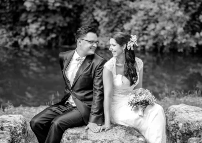 Brautpaarshooting im Gut Schloss Sulzemoos, lachendes Paar auf Stein sitzend, Hochzeitsfotografie.